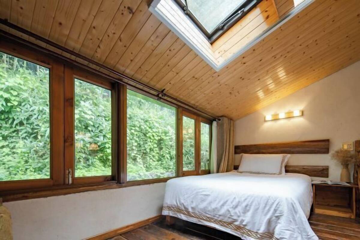 Un dormitorio con una cama grande, techo de madera y varias ventanas.