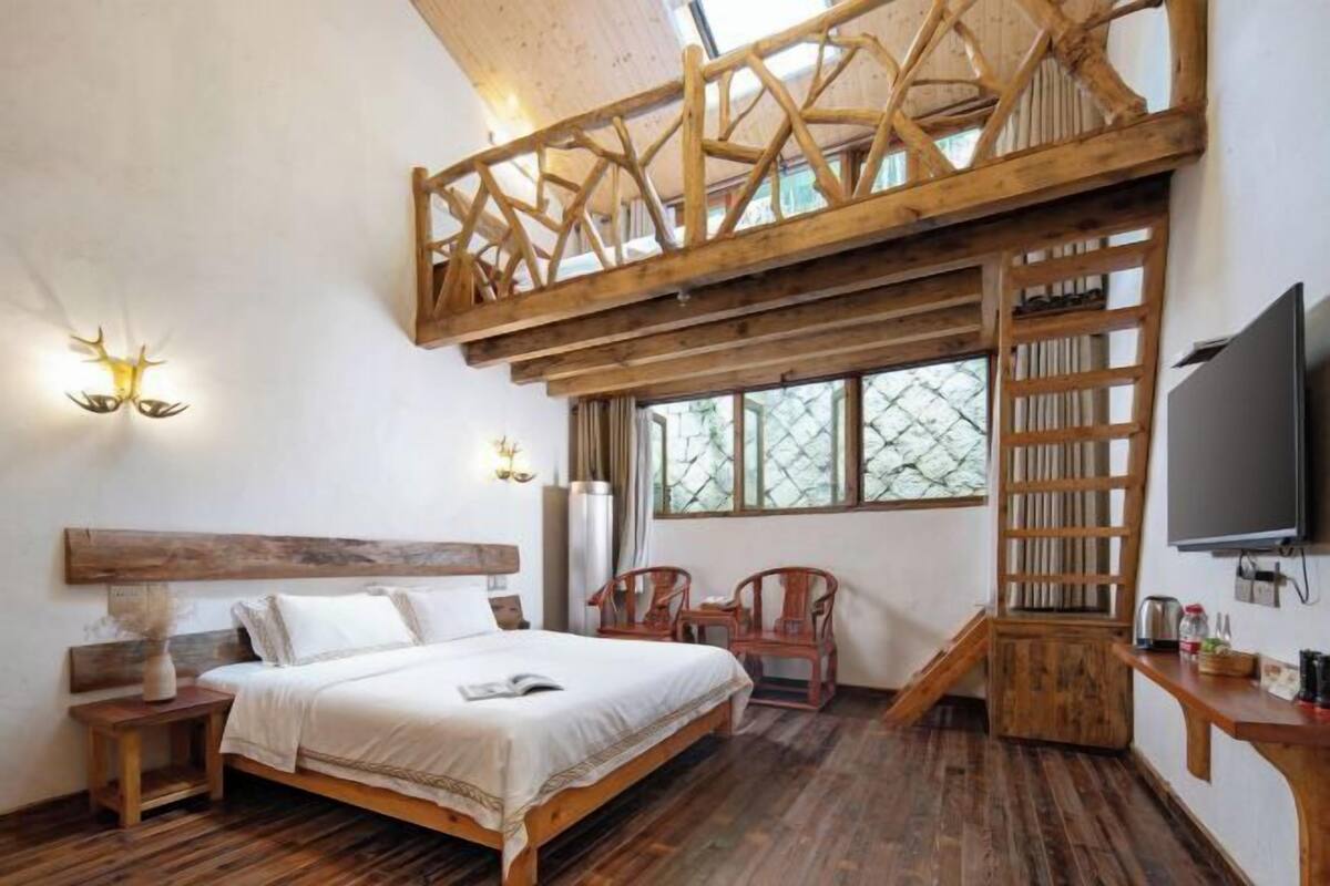 Un dormitorio con cama estilo altillo, muebles de madera, televisión y ventana con vistas.