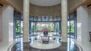 A spacious lobby with a central round table, large pillars, and a view of greenery outside. - Haitang Bay Hongtai Seaview Holiday Apartment (Lingshui)