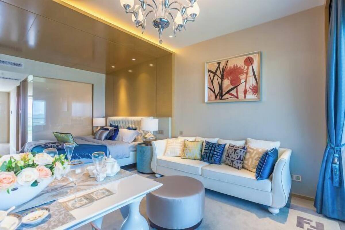 Un salon moderne avec un canapé, un pouf et une table à manger agrémentée de fleurs et de verres.