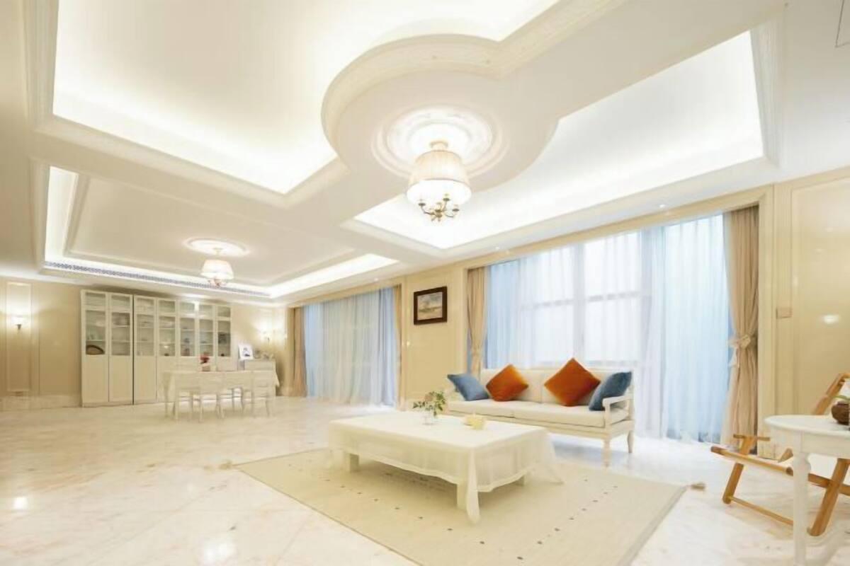 Un salon spacieux avec un canapé blanc, une table basse et un coin repas comprenant une table et des chaises blanches.