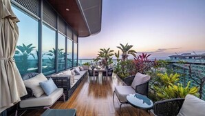 A modern outdoor lounge area with a wooden floor, seating arrangements, and potted plants. - Haitang Bay Hongtai Seaview Holiday Apartment (Lingshui)