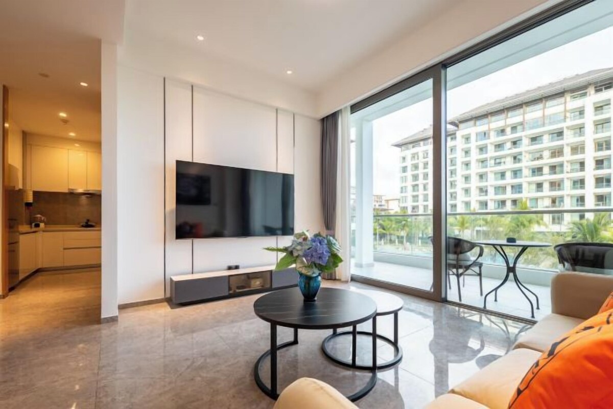 Una sala de estar moderna con una televisión de pantalla plana, una mesa de centro redonda y un sofá.