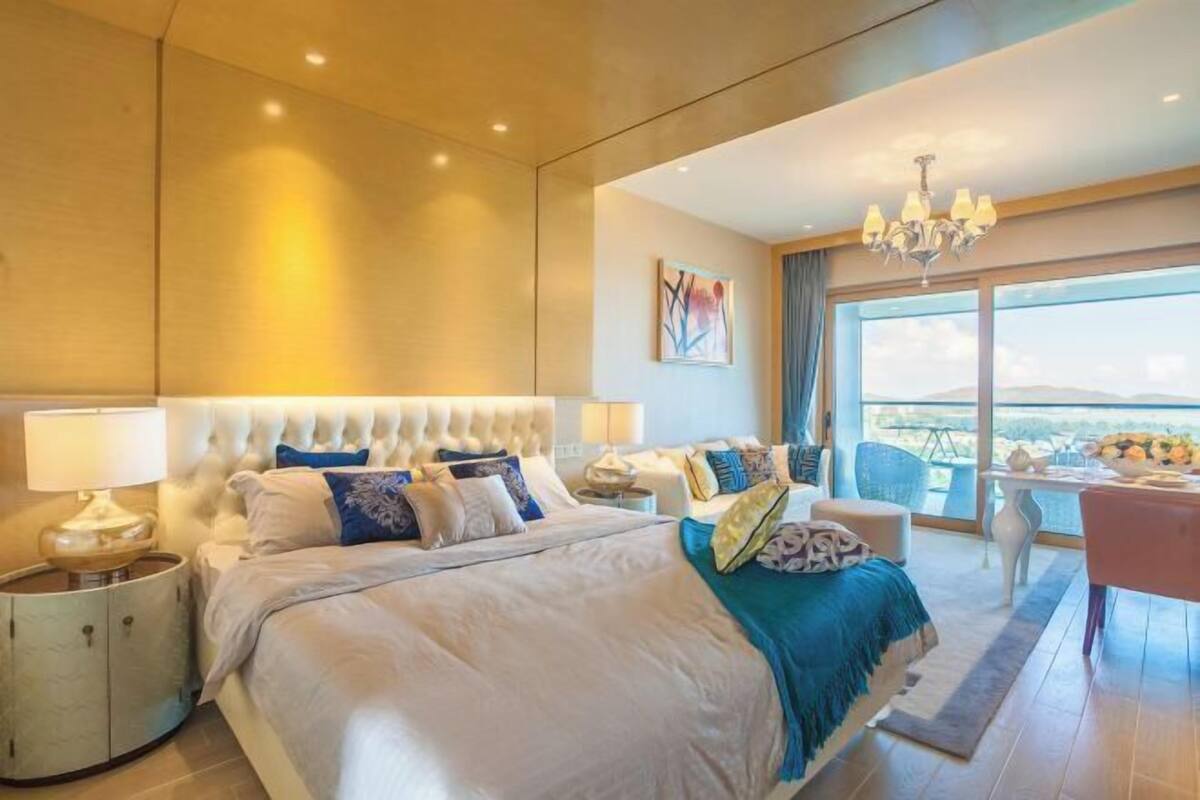 Une chambre d’hôtel moderne dotée d’un grand lit, d’un lustre, d’un coin repas et offrant une vue sur la ville.