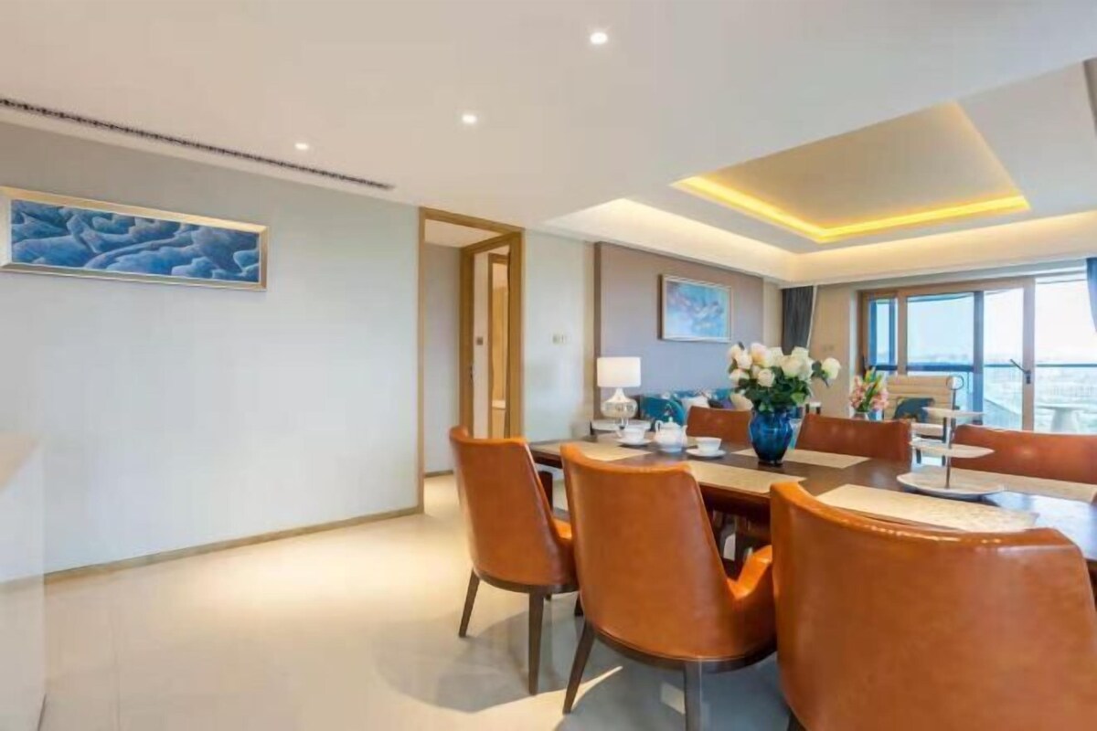 A modern dining area with a round table, brown leather chairs, and a vase of flowers.