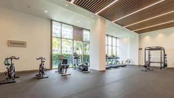 Un gimnasio con equipo de ejercicio, amplias ventanas y un diseño moderno en el techo.