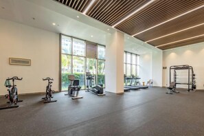 A gym with exercise equipment, large windows, and a modern ceiling design. - Jti seaview resort (Lingshui)
