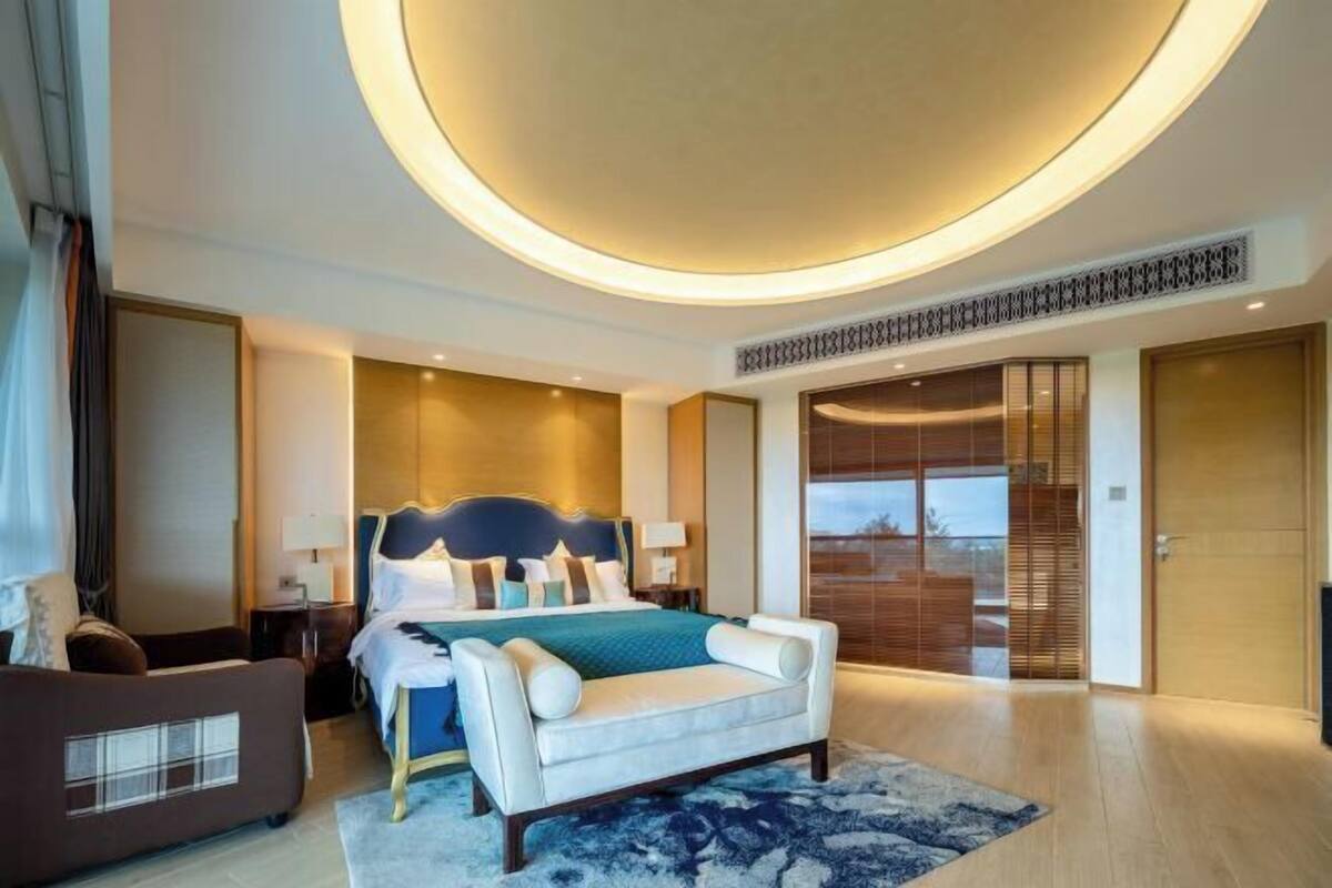Une chambre d’hôtel moderne, dotée d’un grand lit, d’un canapé, d’un bureau et offrant une vue sur l’extérieur.