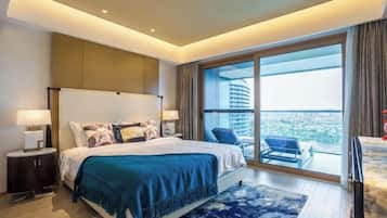 A modern hotel room with a large bed, a nightstand, a desk, and a balcony with a view of the city.