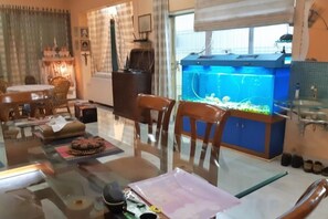 A dining area with a glass table, chairs, and a blue aquarium. - Ish Atithya Corporate Serviced Apartments with Modular Kitchens in Lucknow, IN (Lucknow)