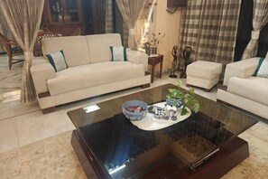 A living room with a sofa, armchairs, a glass coffee table, and a small side table. - Ish Atithya Corporate Serviced Apartments with Modular Kitchens in Lucknow, IN (Lucknow)