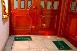 A wooden double door with a 'WELCOME' mat in front. - Ish Atithya Corporate Serviced Apartments with Modular Kitchens in Lucknow, IN (Lucknow)
