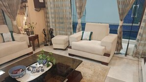 Un soggiorno con due divani beige, un tavolino in vetro e un tappeto decorato.