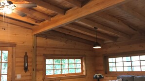 A wooden interior with a ceiling fan, a sofa, a chair, and a table.