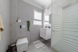 A modern bathroom with a toilet, sink, and shower area.