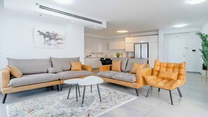 Una sala moderna con un sofá modular, una mesita de centro y un sillón naranja.