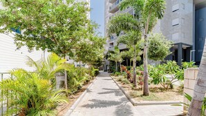Un sendero bordeado de árboles y plantas que conduce a un edificio moderno con balcones.