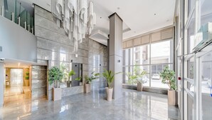 Un vestíbulo amplio con piso de mármol pulido, ventanas grandes y plantas en macetas.