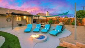 A backyard with lounge chairs, a fire pit, and a covered patio area. - Bermuda Palms: Pool, Spa, Arcade Game, Fire pit! (Bermuda Dunes)