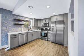 Una cocina moderna con armarios grises, electrodomésticos de acero inoxidable y salpicadero decorativo.