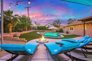 A backyard with a swimming pool, lounge chairs, and a fire pit. - Bermuda Palms: Pool, Spa, Arcade Game, Fire pit! (Bermuda Dunes)
