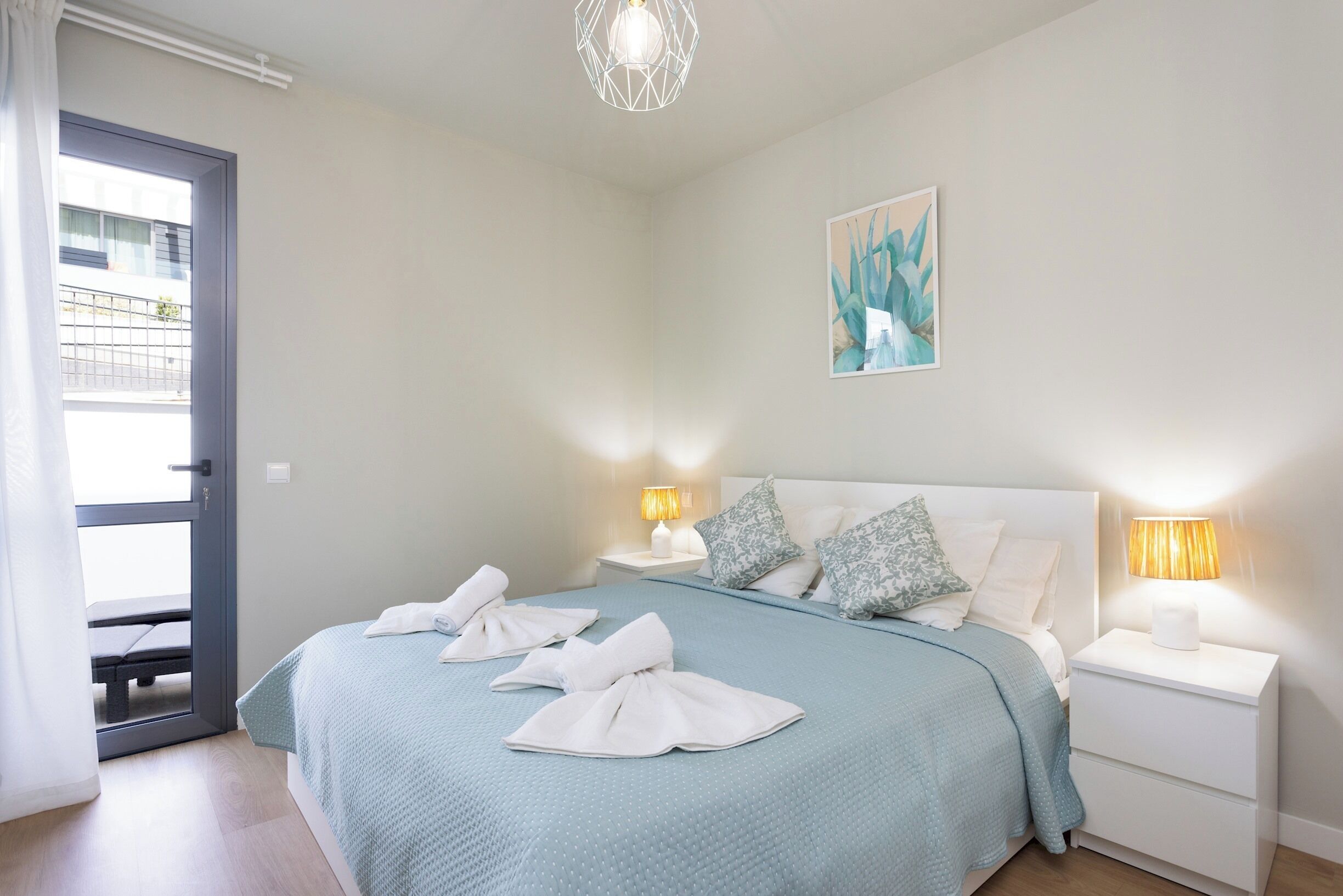 Une chambre d’hôtel avec un lit, deux tables de chevet, une porte et une fenêtre.