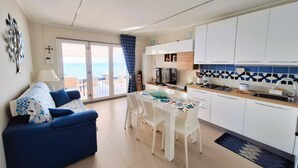 A modern kitchen with white cabinets, a dining table with chairs, and a view to the outside.