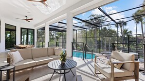A modern outdoor living area with a sofa, a round table, and a pool view.