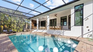 A modern indoor pool with clear glass walls, a sun terrace, and lounge chairs.