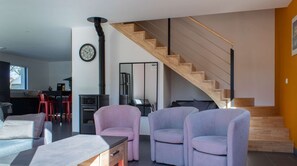 Ein modernes Wohnzimmer mit Treppe, Essbereich und Küche.