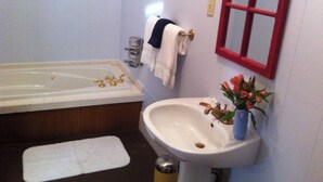 A bathroom with a bathtub, sink, and a mirror. - Charming 1-bedroom house in Historic Mineola, short walk to town (Mineola)