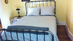 A bed with a metal frame, two pillows, and a striped bedspread. - Charming 1-bedroom house in Historic Mineola, short walk to town (Mineola)