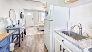 A compact kitchen with a refrigerator, sink, and a dining area with a table and chairs. - Walk to the Beach | 2 Pools | Military Welcome! (Biloxi)