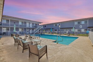 A pool area with lounge chairs and a staircase leading to an upper level.