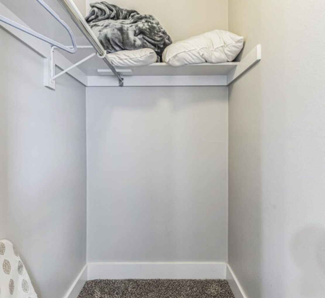 Una stanza piccola e stretta con un letto a castello, uno scaffale bianco sottostante e pavimento tappezzato.