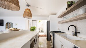 Uma cozinha moderna com uma ilha central, eletrodomésticos embutidos e prateleiras de madeira.