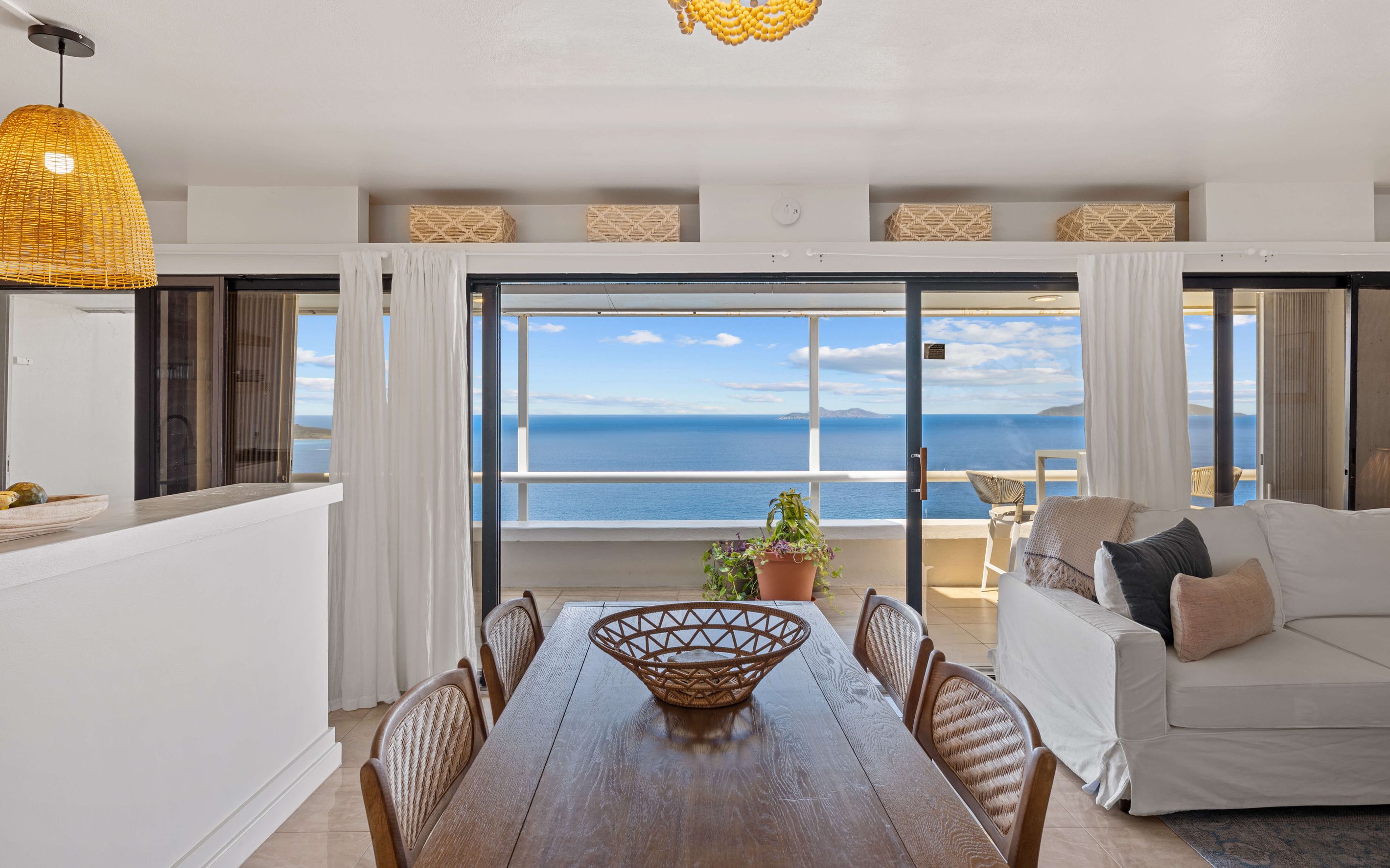 Ein Essbereich mit Meerblick, ein Balkon mit einer Couch und einer hängenden Leuchte.