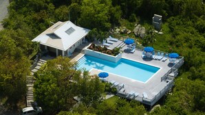 Vista aérea de um resort com piscina, área de estar e um edifício com telhado inclinado.