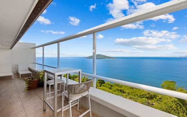 A balcony with a view of the sea and a small island.