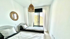 Een slaapkamer met twee bedden, een hanglamp, een spiegel en een raam met gordijnen.