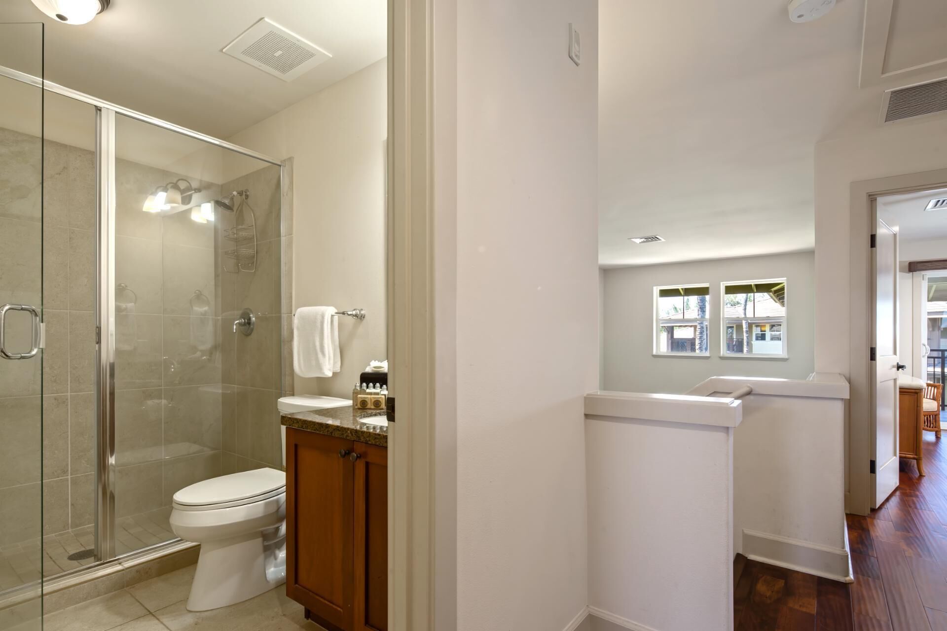 A modern bathroom with a glass shower enclosure, a toilet, and a vanity with a mirror.