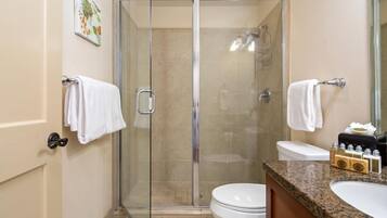 Une salle de bain moderne avec une douche à parois de verre, des toilettes et un lavabo équipé de produits de toilette.