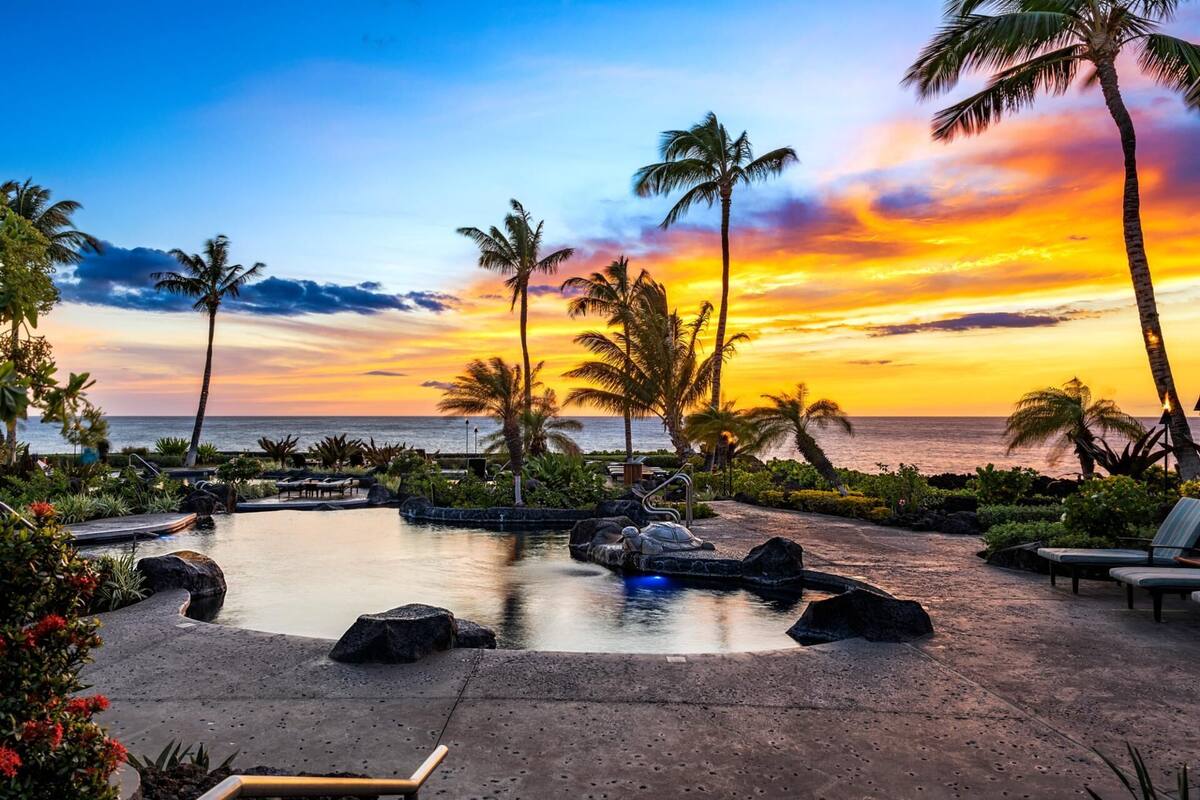Um resort com piscina, espreguiçadeiras e palmeiras.