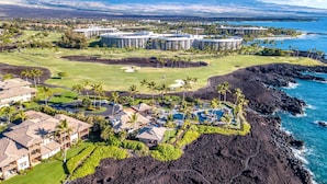 A resort with multiple buildings, a golf course, and a coastline. - Halii Kai Resort by KBM (Waikoloa)