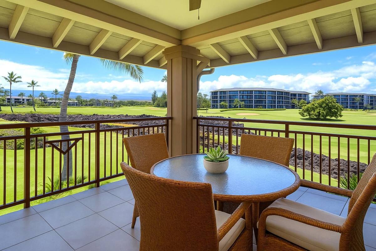 Uma área de estar coberta ao ar livre, com cadeiras de vime e uma mesa, com vista para um campo de golfe e edifícios.