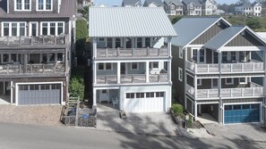 A multi-story residential building with a central entrance, a garage, and a balcony on the second floor. - Ocean-View Home- Private Hot Tub, Chefs Kitchen, Double Patio, Dog Friendly (Pacific Beach)