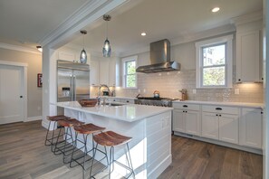 A spacious kitchen with a large island, white cabinetry, and a stainless steel range hood. - Ocean-View Home- Private Hot Tub, Chefs Kitchen, Double Patio, Dog Friendly (Pacific Beach)