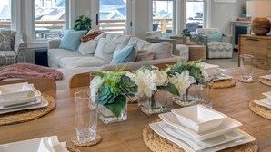 A dining area with a wooden table set for four, surrounded by wicker placemats and white plates. - Ocean-View Home- Chefs Kitchen,  Private Hot Tub, Dog Friendly, Double Patio (Pacific Beach)