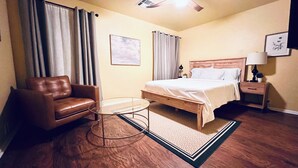 A hotel room with a bed, a chair, a small table, a nightstand, and a ceiling fan. - Charming 3-bedroom townhome, BMT Lackland, near SeaWorld, & 15mins to Downtown (San Antonio)