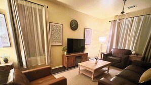 A living room with a sofa, armchair, coffee table, TV, and curtains. - Charming 3-bedroom townhome, BMT Lackland, near SeaWorld, & 15mins to Downtown (San Antonio)
